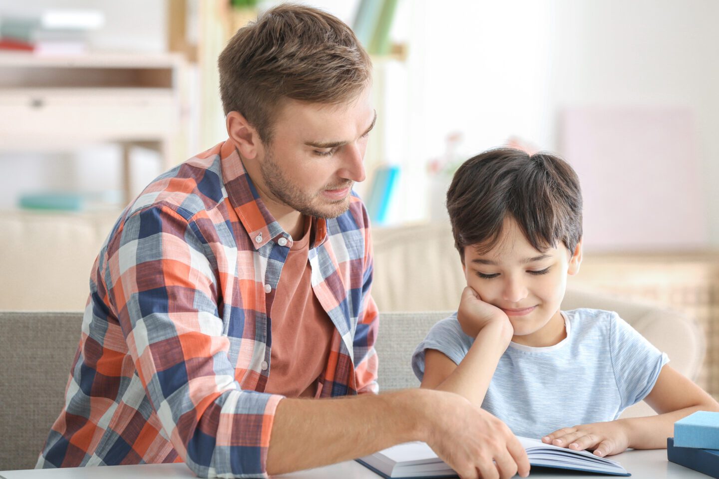 man and young boy paired reading a book at home