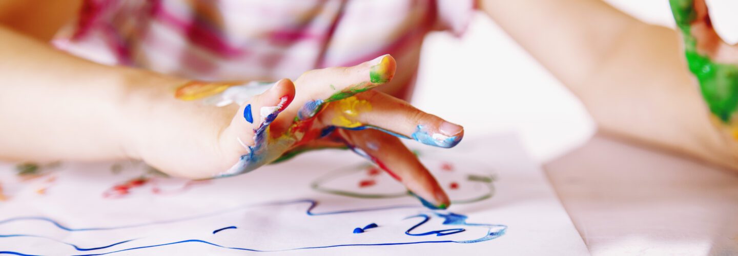 Close up young girl painting with colorful hands. Art, creativity and painting concept.