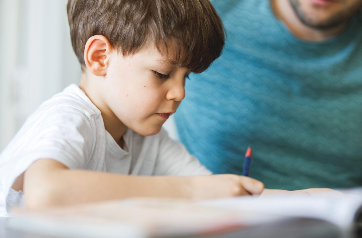 schoolboy building confidence by doing homework with his tutor.